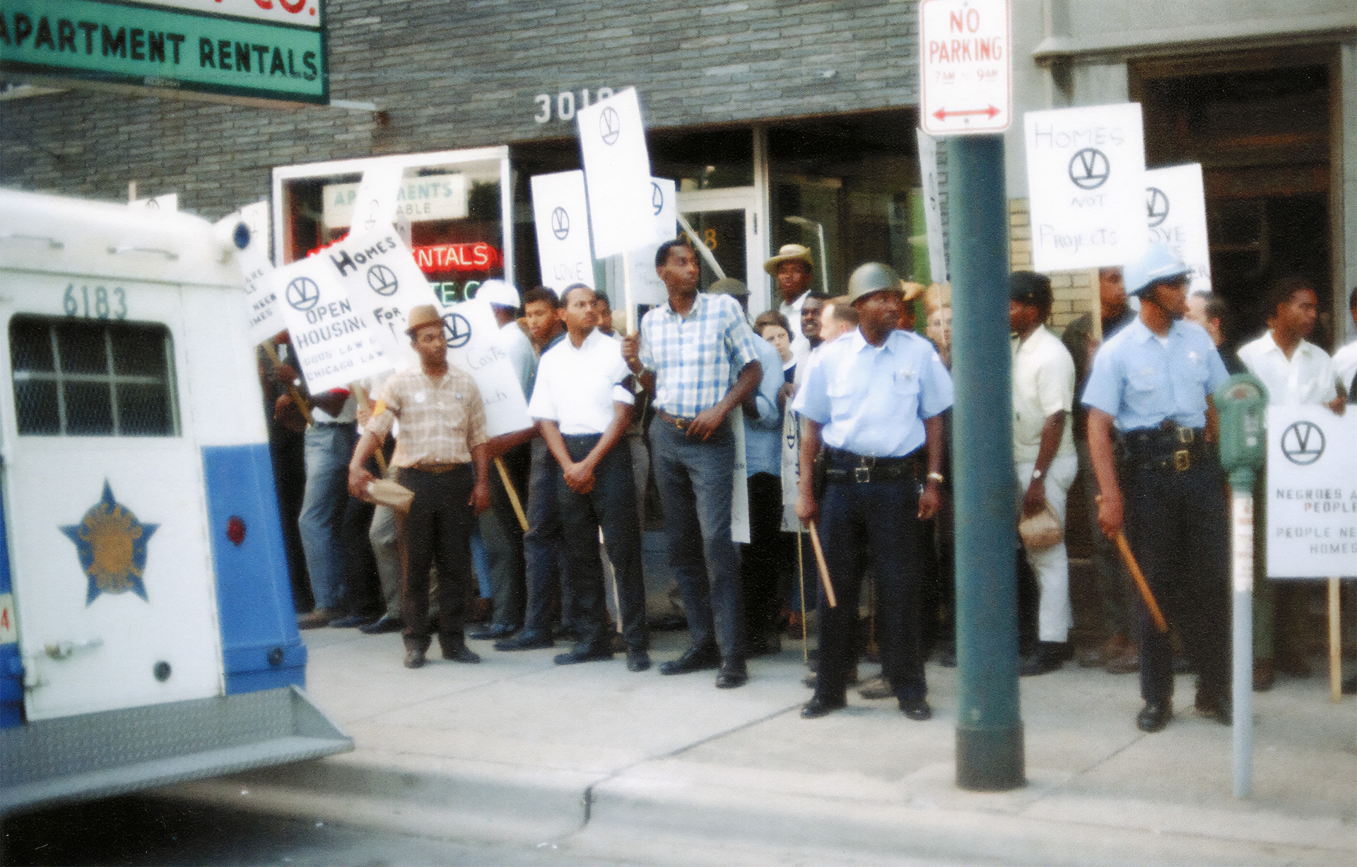 Protests at Chicago real estate offices were a common part of the Chicago Freedom Movement. The signs feature the "End the Slums" emblem that appeared on many materials during these protests.